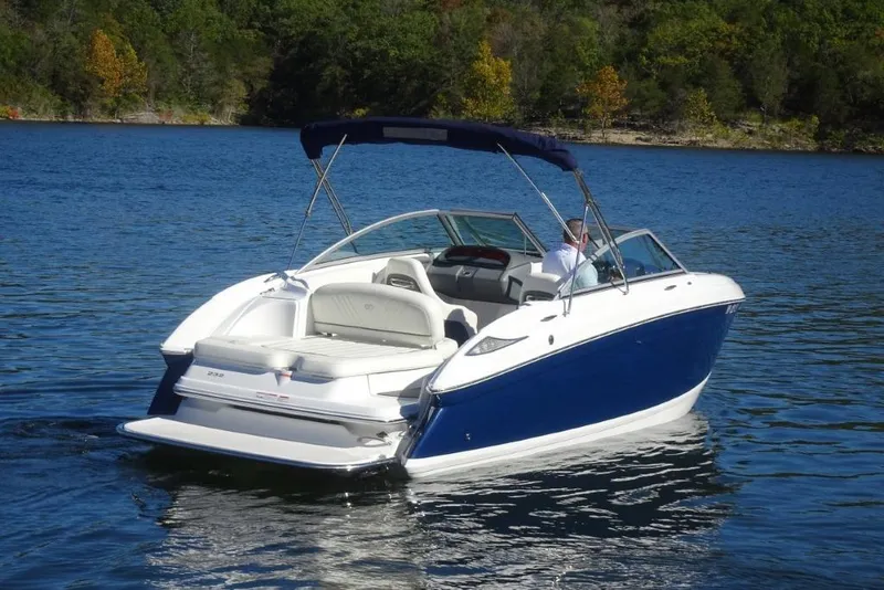 Slide: The Image of 2008 Cobalt 232 boat on a serene lake with lush green shoreline. - 2