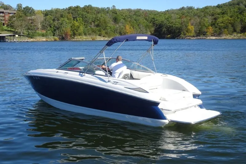 Slide: The Image of 2008 Cobalt 232 boat cruising on a scenic lake with lush green shoreline. - 5