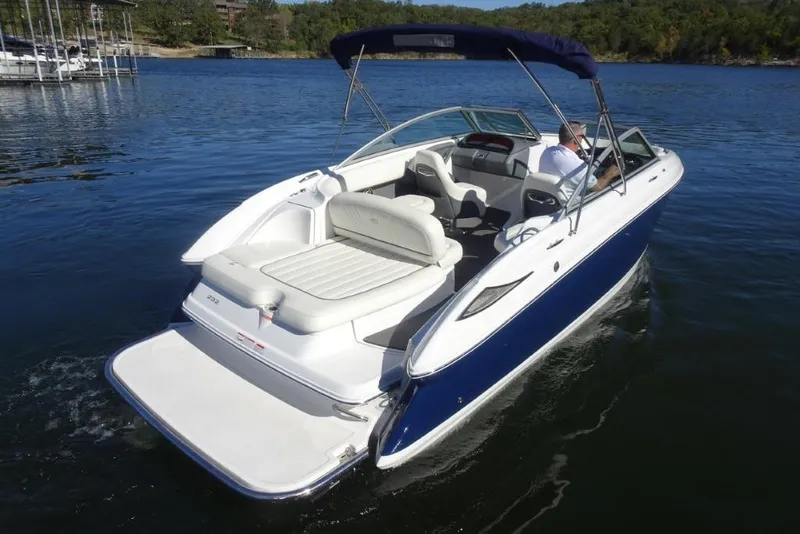 Slide: The Image of 2008 Cobalt 232 boat cruising on a serene lake with lush green shoreline. - 8