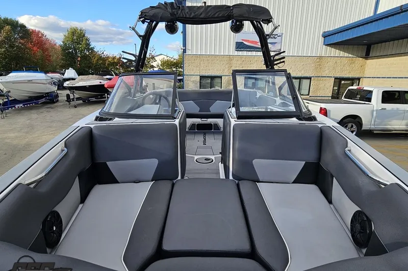 Slide: The Image of 2020 Moomba Max boat interior with gray seating, parked outdoors near other boats. - 18