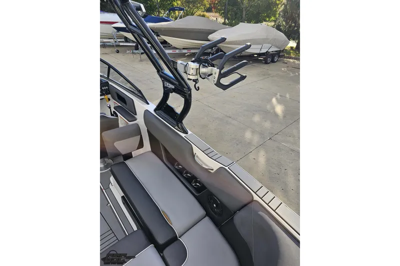 Slide: The Image of 2020 Moomba Max boat interior with seating and wakeboard rack, parked on concrete. - 48