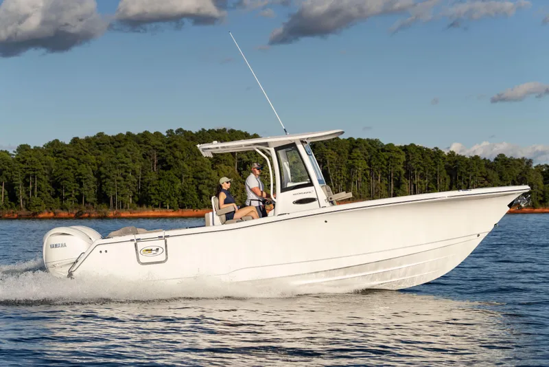 Slide: The Image of 2026 Sea Hunt Ultra 275 Coffin Box boat cruising on a lake with forested shoreline. - 10