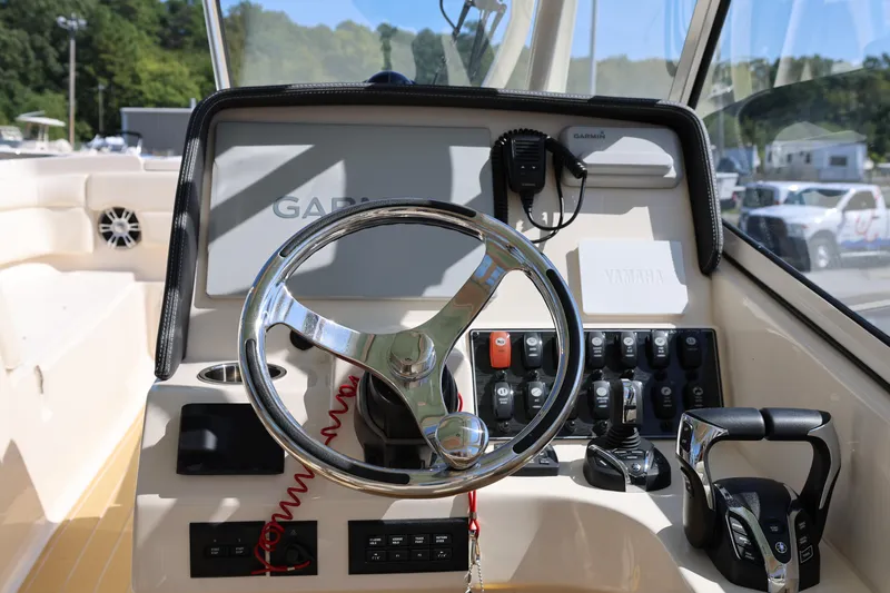 Slide: The Image of 2025 Grady-White Freedom 275 boat dashboard with steering wheel and controls. - 13