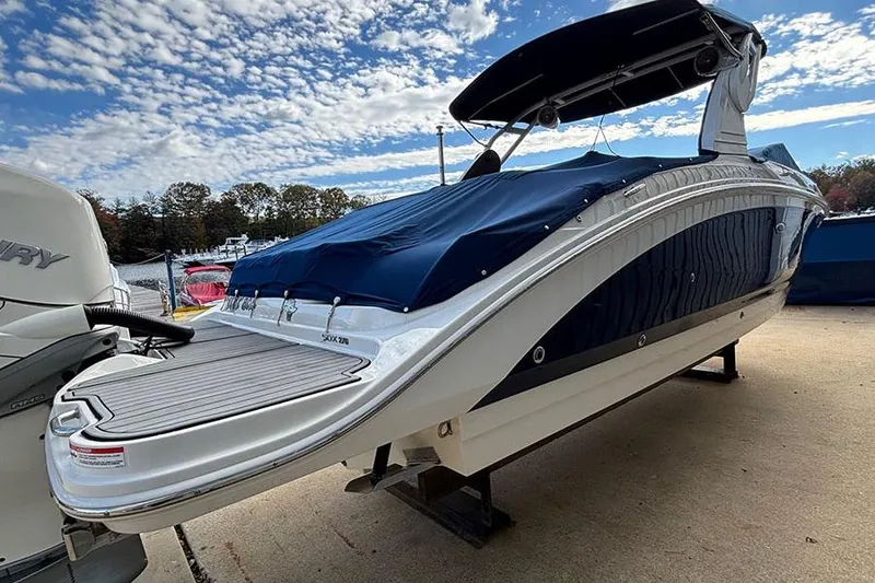 Slide: The Image of 2018 Sea Ray SDX 270 Outboard boat with blue cover, docked under a partly cloudy sky. - 4