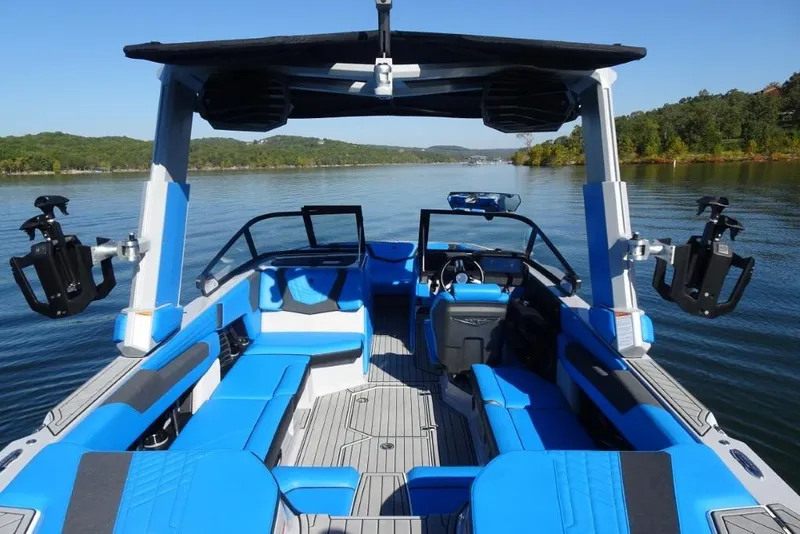 Slide: The Image of 2024 Nautique Super Air Nautique G23 boat interior with blue seating on a calm lake. - 15