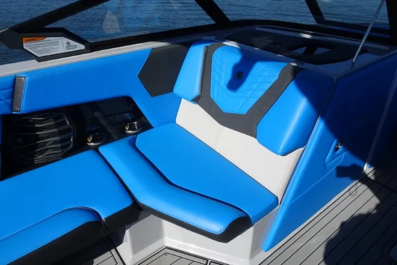 Slide: The Image of 2024 Nautique Super Air Nautique G23 interior with blue and white seating, cup holders, and speaker. - 25