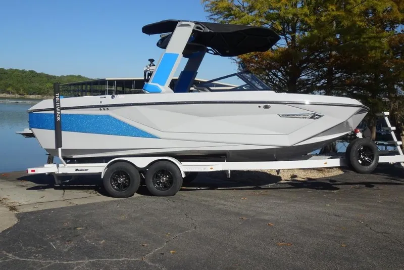 Slide: The Image of 2024 Nautique Super Air Nautique G23 boat on trailer by a lake. - 3
