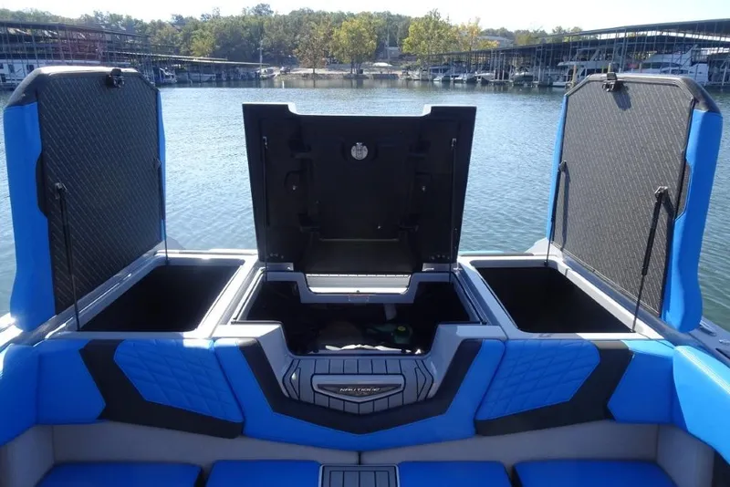 Slide: The Image of 2024 Nautique Super Air Nautique G23 boat with open storage compartments on a lake. - 33