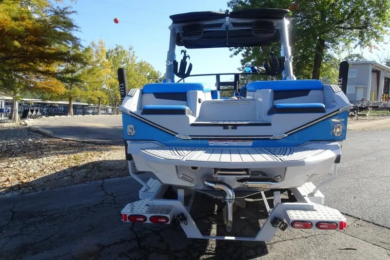 Slide: The Image of 2024 Nautique Super Air Nautique G23 boat, rear view, blue and white design, parked outdoors. - 5
