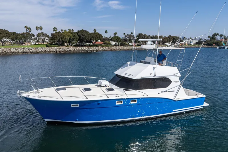 The Image of 1974 Hatteras Convertible Sportfisher boat on calm water, blue hull, scenic background. - 1