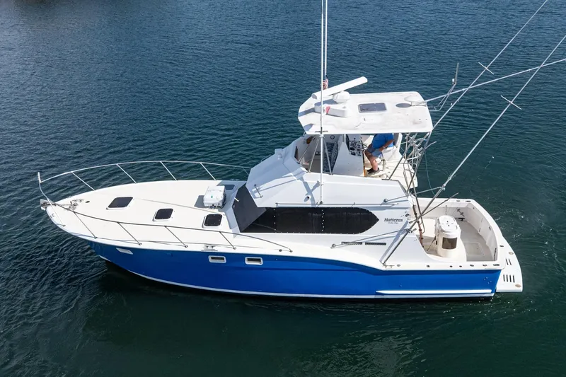 Slide: The Image of 1974 Hatteras Convertible Sportfisher boat on calm water, featuring a sleek blue and white design. - 11