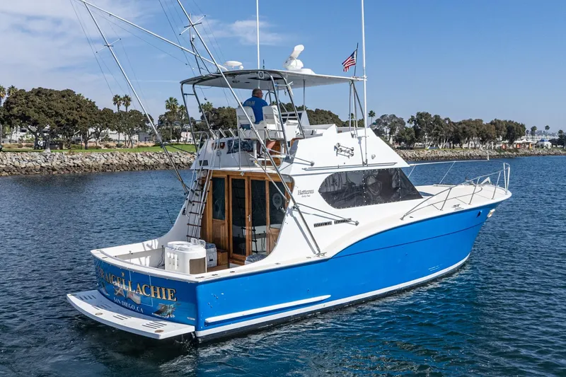 Slide: The Image of 1974 Hatteras Convertible Sportfisher boat on water, blue and white design, coastal background. - 13