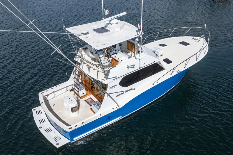 Slide: The Image of 1974 Hatteras Convertible Sportfisher boat on water, featuring a blue and white design. - 15