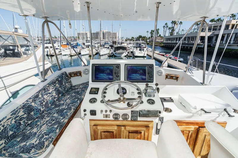 Slide: The Image of 1974 Hatteras Convertible Sportfisher yacht helm with marina view, featuring navigation equipment. - 17
