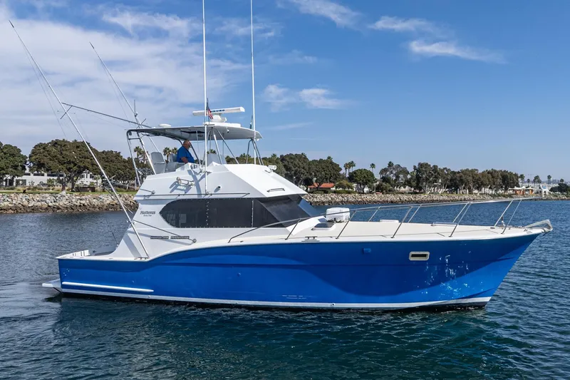 Slide: The Image of 1974 Hatteras Convertible Sportfisher boat on water, blue hull, clear sky background. - 3