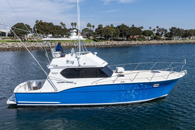 Slide: The Image of 1974 Hatteras Convertible Sportfisher boat on water, blue and white design, scenic background. - 4
