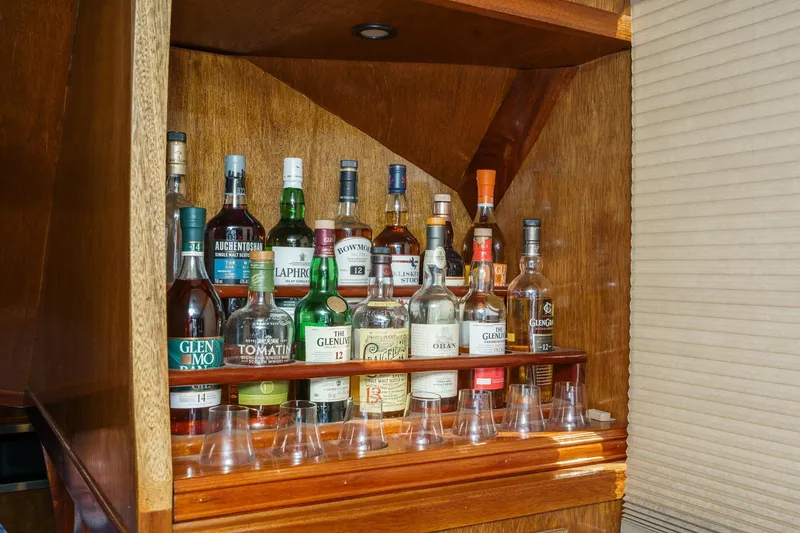 Slide: The Image of Collection of whiskey bottles in a wooden cabinet on a 1974 Hatteras Convertible Sportfisher. - 41