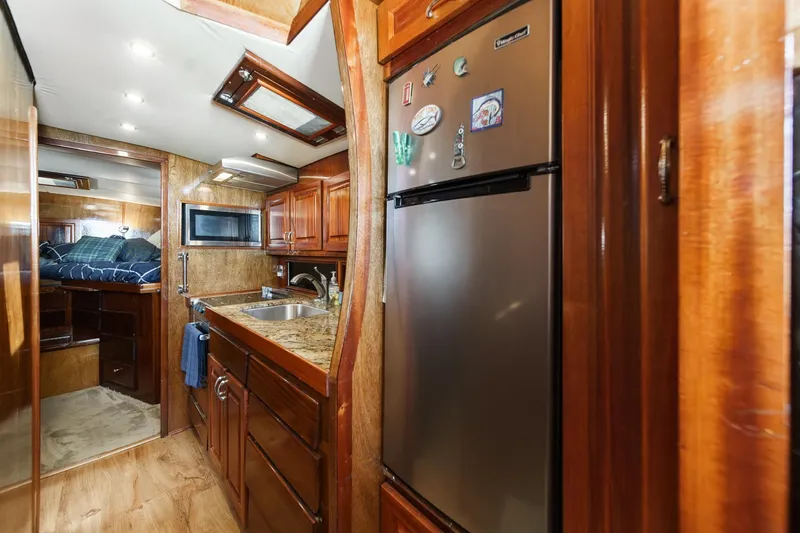 Slide: The Image of 1974 Hatteras Convertible Sportfisher interior with kitchen, wood cabinetry, and cozy sleeping area. - 42