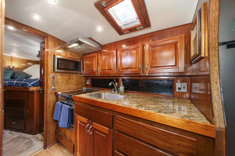 Slide: The Image of 1974 Hatteras Convertible Sportfisher interior with wooden cabinetry and granite countertops. - 43