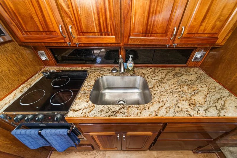 Slide: The Image of 1974 Hatteras Convertible Sportfisher kitchen with granite countertop, stove, and wooden cabinets. - 44