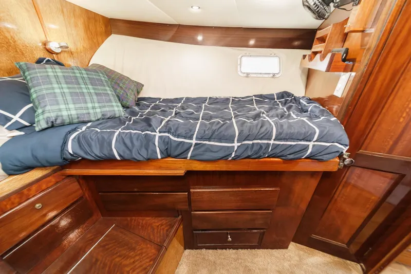Slide: The Image of 1974 Hatteras Convertible Sportfisher cabin with cozy bed and wooden storage drawers. - 49