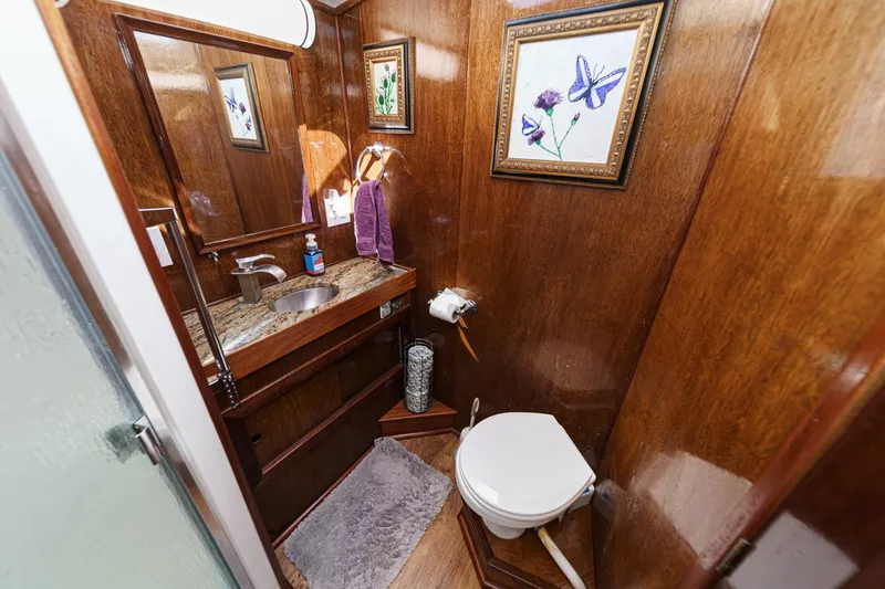 Slide: The Image of 1974 Hatteras Convertible Sportfisher bathroom with wood paneling, granite sink, and floral artwork. - 51