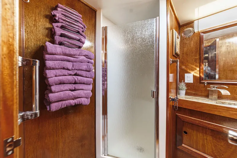 Slide: The Image of 1974 Hatteras Convertible Sportfisher bathroom with wooden decor, purple towels, and glass shower door. - 52