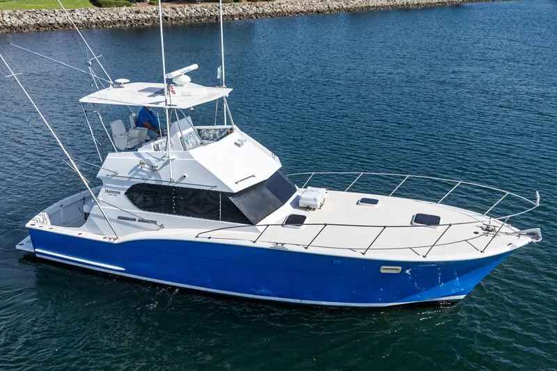 Slide: The Image of 1974 Hatteras Convertible Sportfisher boat on calm water, featuring a sleek blue and white design. - 6