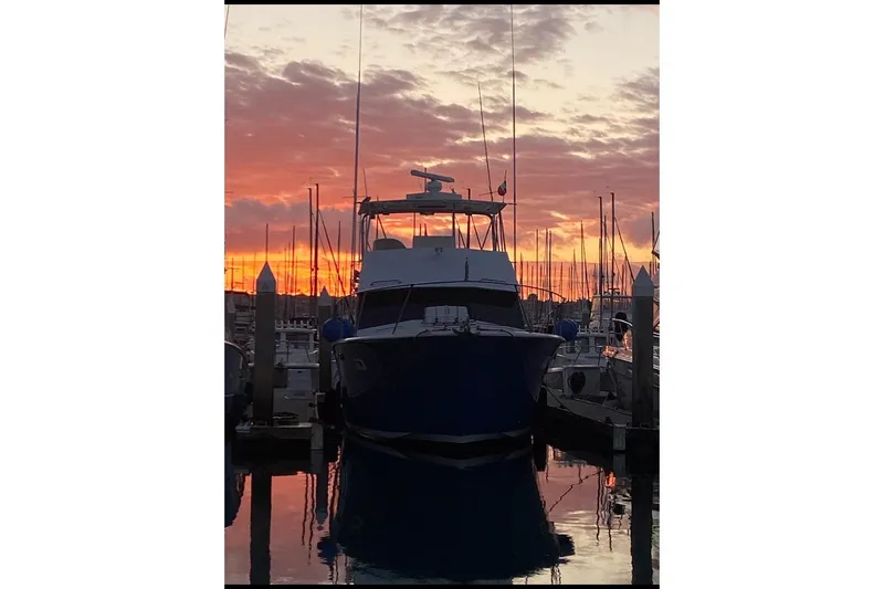 Slide: The Image of 1974 Hatteras Convertible Sportfisher at sunset in marina, silhouetted against vibrant sky. - 61