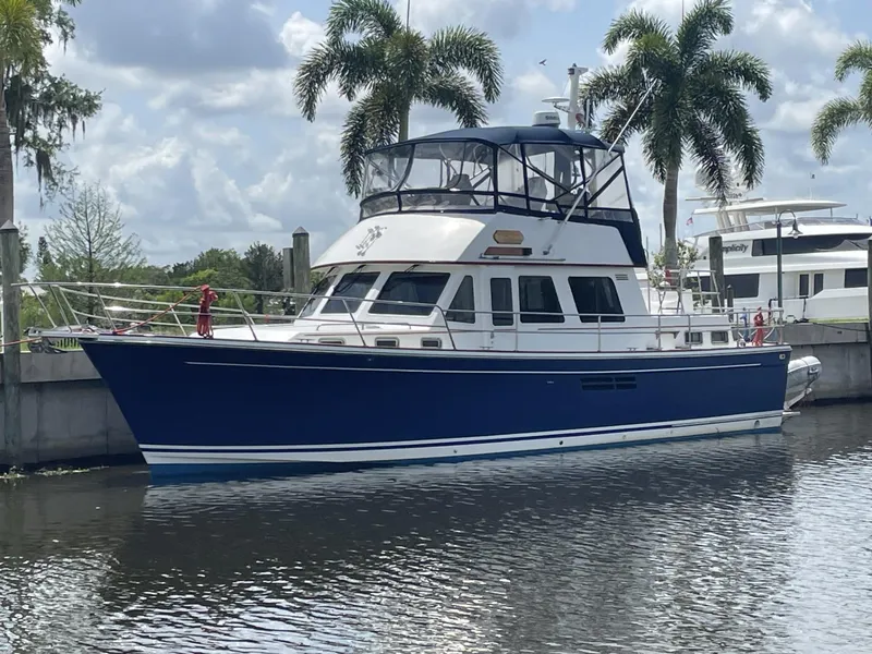 Slide: The Image of 2001 Sabre Sabreline 43 yacht docked by palm trees under a cloudy sky. - 0