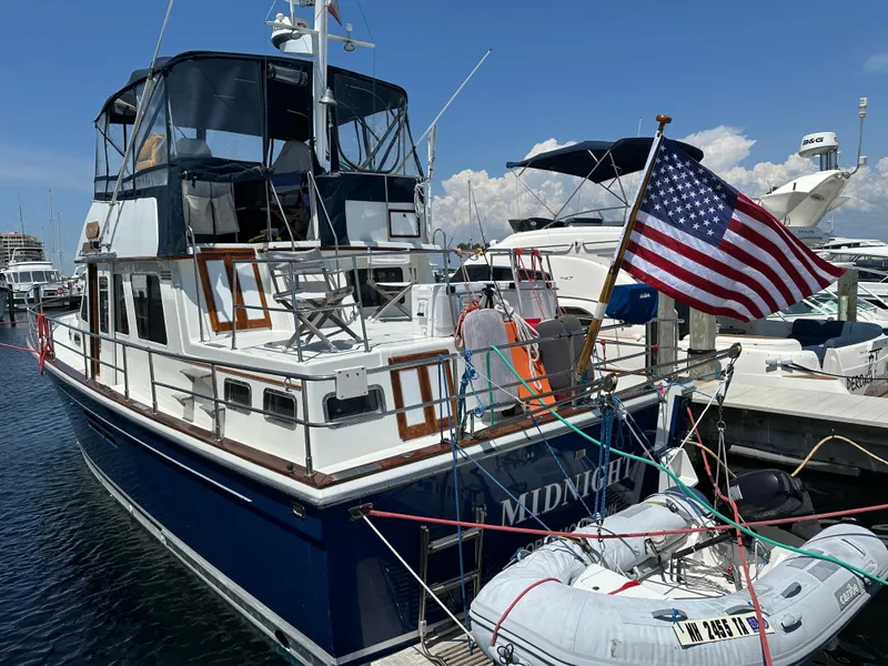 Slide: The Image of 2001 Sabre Sabreline 43 yacht docked, displaying American flag, with inflatable boat attached. - 1