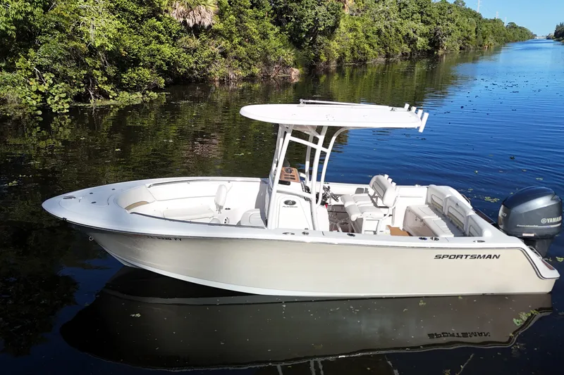 The Image of 2015 Sportsman Heritage 231 Center Console boat on a calm river, surrounded by lush greenery. - 0