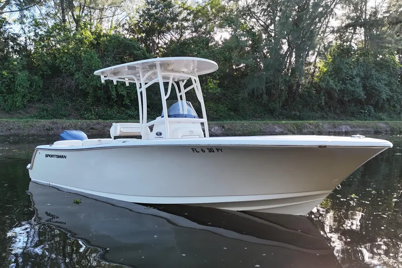Slide: The Image of 2015 Sportsman Heritage 231 Center Console boat on calm water, surrounded by lush greenery. - 1