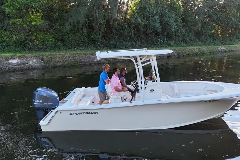 Slide: The Image of 2015 Sportsman Heritage 231 Center Console boat with three people cruising on a calm river. - 10