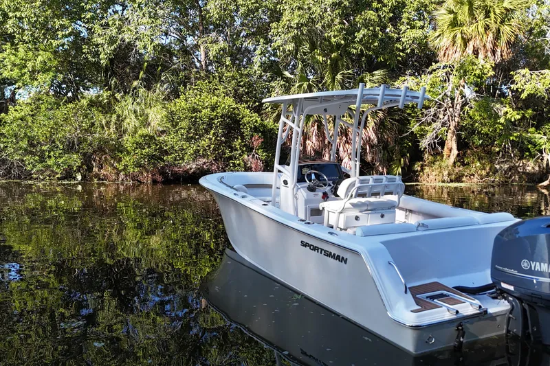 Slide: The Image of 2015 Sportsman Heritage 231 Center Console boat on calm water, surrounded by lush greenery. - 11