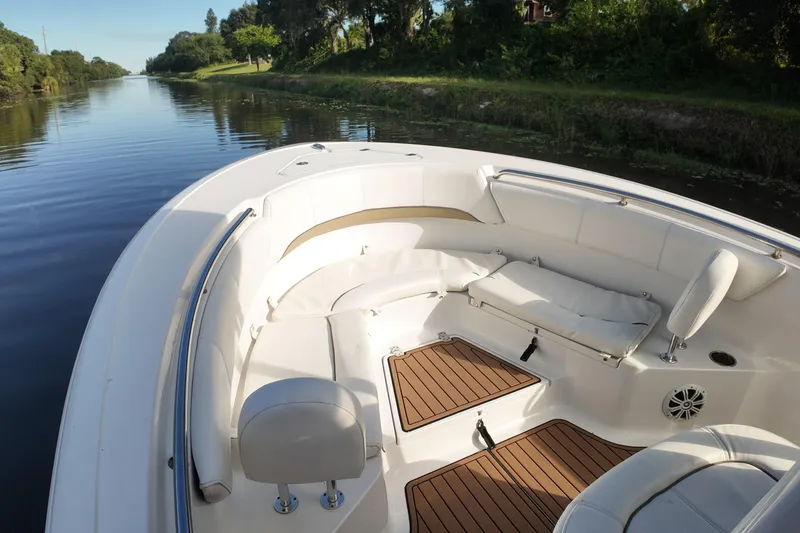 Slide: The Image of 2015 Sportsman Heritage 231 Center Console boat interior with cushioned seating on a calm river. - 15