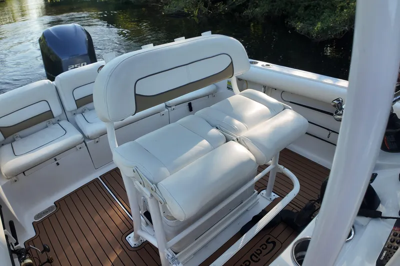 Slide: The Image of 2015 Sportsman Heritage 231 Center Console boat interior with white seating and wood flooring. - 22