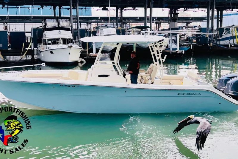 The Image of 2017 Cobia 296 Center Console boat docked, with a pelican flying nearby. - 11