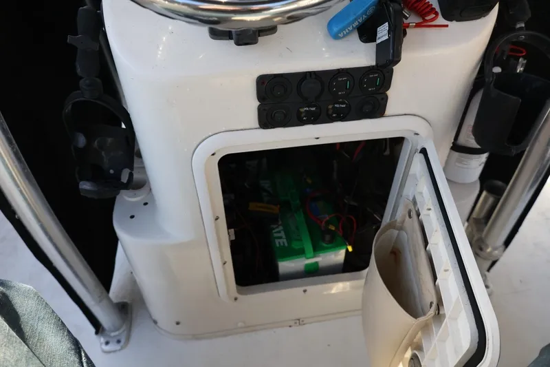 Slide: The Image of 2013 Carolina Skiff 178 DLV console with open storage compartment and visible battery. - 26