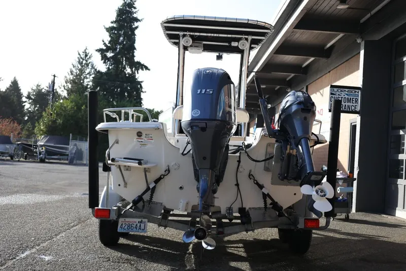 Slide: The Image of 2013 Carolina Skiff 178 DLV boat with dual outboard motors, parked near a building. - 6
