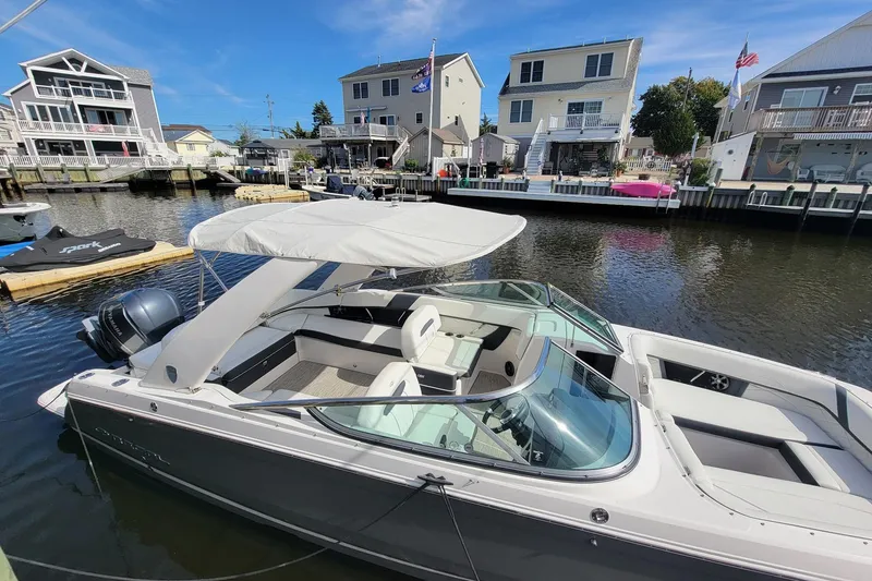 Slide: The Image of 2018 Regal 26 OBX boat docked in a residential canal under a clear blue sky. - 1
