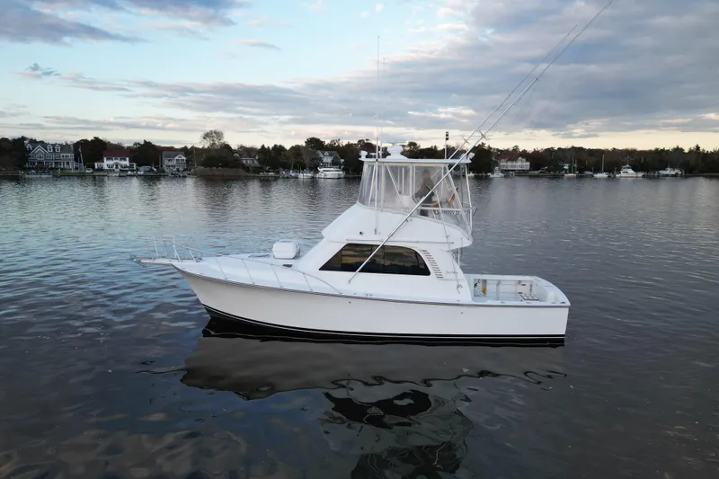Slide: The Image of 2004 Henriques 35 Sportfisherman boat on calm water, with scenic shoreline background. - 1