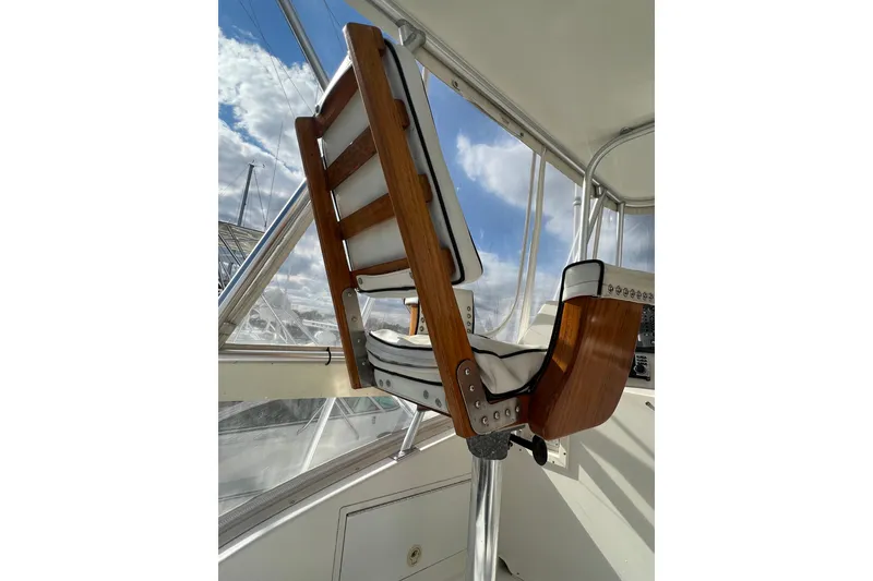 Slide: The Image of Captain's chair on 2004 Henriques 35 Sportfisherman, showcasing wooden design and white upholstery. - 111
