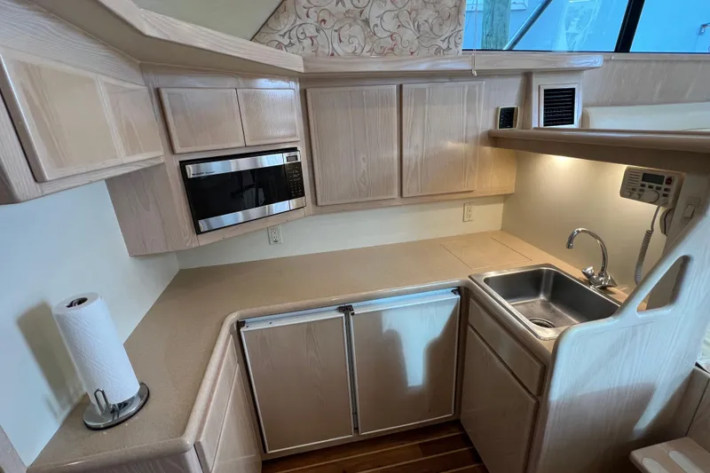 Slide: The Image of 2004 Henriques 35 Sportfisherman kitchen with microwave, sink, and wooden cabinetry. - 52