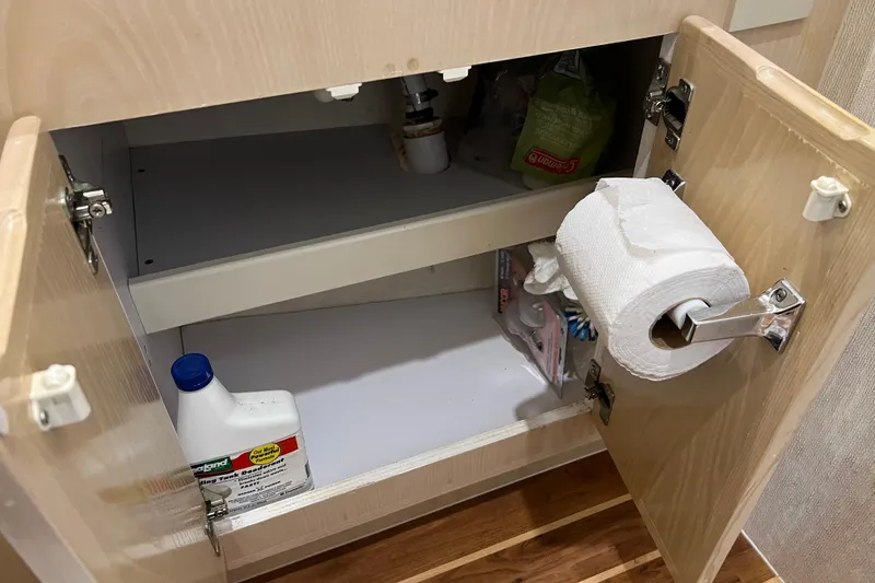 Slide: The Image of Open cabinet with cleaning supplies and toilet paper in a 2004 Henriques 35 Sportfisherman. - 68