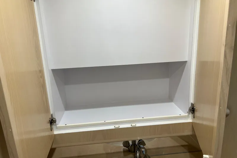 Slide: The Image of Open wooden cabinet with white interior and visible plumbing underneath. - 69