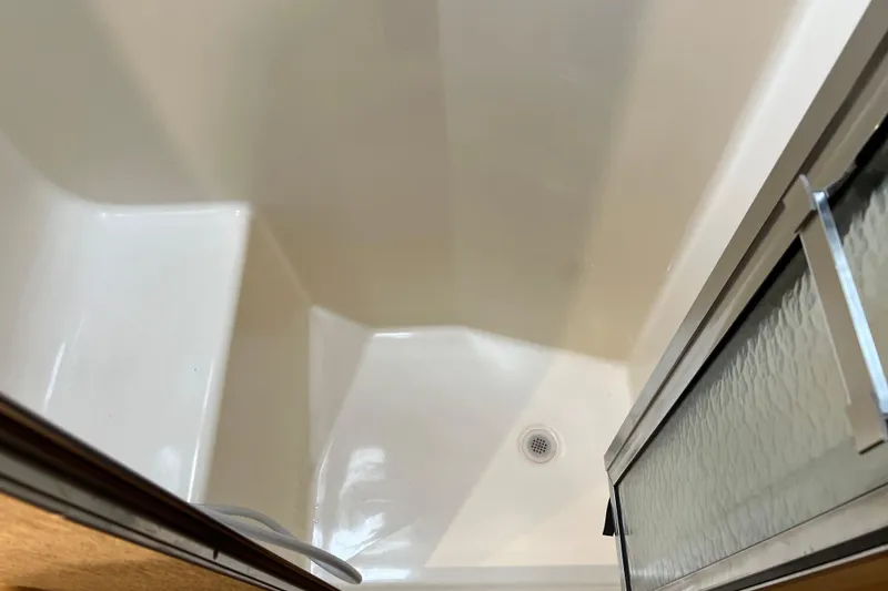 Slide: The Image of Shower area inside a 2004 Henriques 35 Sportfisherman boat, featuring a drain and sliding door. - 72