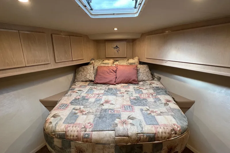 Slide: The Image of 2004 Henriques 35 Sportfisherman cabin with floral bedding and overhead storage. - 73