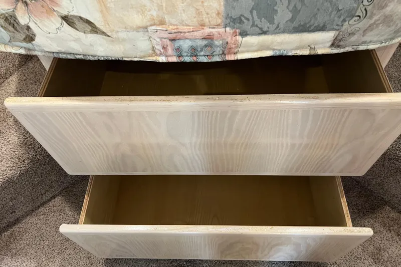 Slide: The Image of Open wooden drawers under a floral-patterned bedspread, revealing empty storage space. - 75