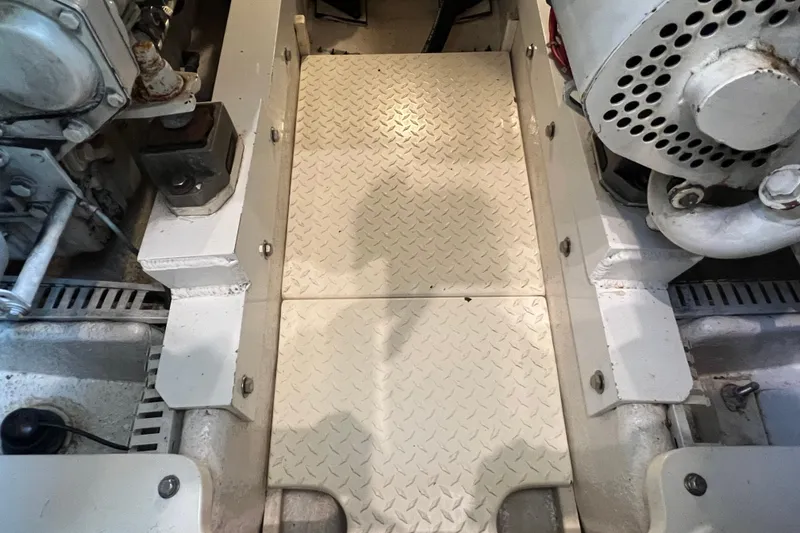 Slide: The Image of Engine room of a 2004 Henriques 35 Sportfisherman, featuring mechanical components and diamond plate flooring. - 84